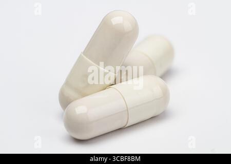 Three white pills, against a white background, stack on top of one another Stock Photo