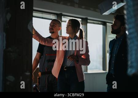 A team of professionals discussing renovation plans in a sunlit construction site Stock Photo