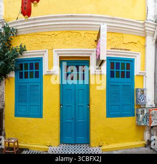 Vibrant yellow heritage building facade with blue doors and shutters windows, featuring a red lantern contrasting colours , kuala lumpur, malaysia Stock Photo