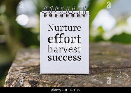 Spiral notepad with motivational words placed on wooden surface with green nature background. Stock Photo