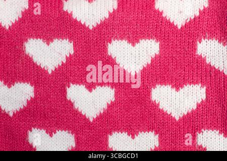 A pink woolen fabric with white hearts in a close up view Stock Photo