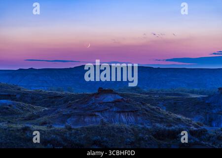 June 30, 2022, Alberta, Canada: The waxing crescent Moon two days after New low in a smoky sky setting over the Badlands of Dinosaur Provincial Park, Alberta, Canada. This was June 30, 2022. Despite the hazy skies, the twilight colours show up well in the sky. The glow of Earthshine shows up slightly on the night side of the Moon. ..This is a blend of a single 3.2-second shot with the RF24-105mm lens at f/4 and 105mm for the sky, with a stack of four longer 13-second exposures for the darker ground at the same lens settings, and with Canon R5 at ISO 200. (Credit Image: © Alan Dyer/VW Pics via Stock Photo
