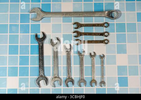 Different size wrenches placed on blue tiles, representing plumbing, repairs, and home improvement tasks Stock Photo