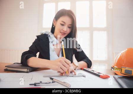Female architect working on blueprint architects project in office. Stock Photo