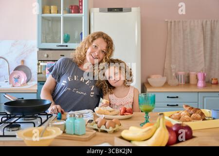 Mother and daughter enjoying weekend breakfast in cozy kitchen Stock Photo