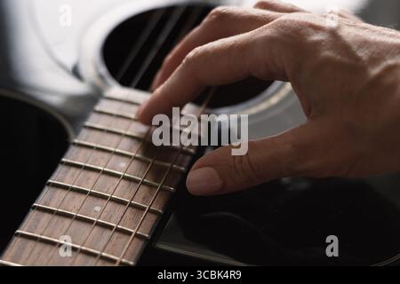 Dark acoustic guitar. Woman learns to play guitar. Musical instrument. Close up Stock Photo