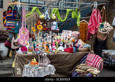 London, UK, 14 May 2025, A outdoor market stall shows a lot of handmade crocheted and knitted items,  bags, blankets, hats, stuffed animals, and decor Stock Photo