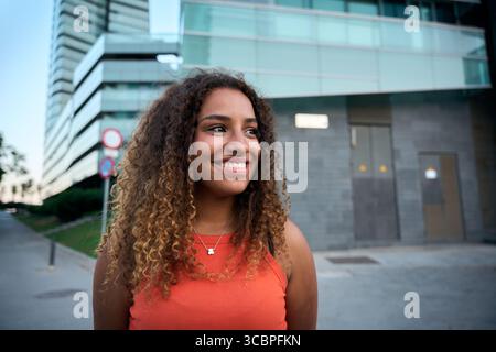 Authentic young woman smiling with joy and confidence in urban setting Stock Photo