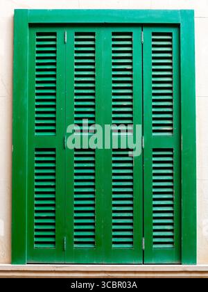 Traditional wooden shuuters on the window, painted in green, typical for Mediterranean architectural style Stock Photo