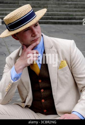 A man in a straw hat and suit is sitting and thinking. Stock Photo