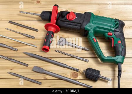 Hammer drill with a set of drill bits on wooden table. Selective focus. Stock Photo