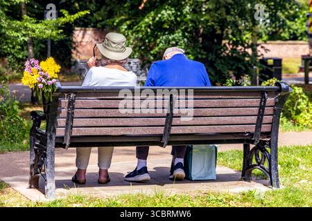Old couple sitting on bench, Levenside, Stokesley, North Yorkshire, England, UK Stock Photo