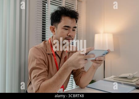 this businessman is relaxing in his office after long day work with his phone, he is spent his free time on his phone in the office, relax, head of ma Stock Photo