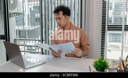 a businessman is in the office, he works in modern office, head of marketing is working with a lot of document, finance manager has been working since Stock Photo