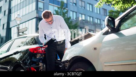 Insurance Adjuster Inspects Car Damage Using Tablet After Accident Stock Photo