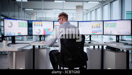 Young Caucasian Male Stock Analyst Using Computer For Market Research. Stock Photo