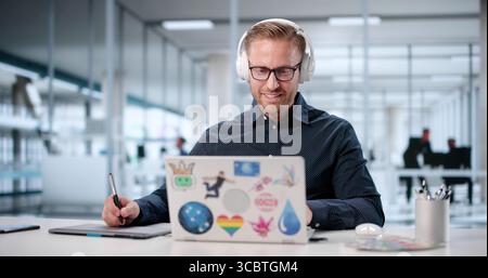 Talented Young Artist Creating Stunning Visual Designs On His Laptop. Stock Photo