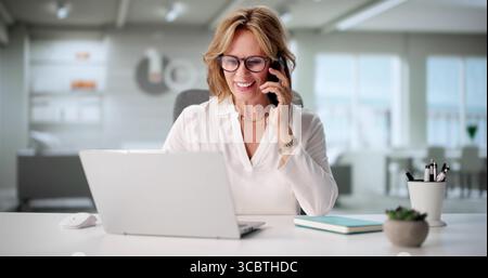 Elderly Woman Speaking With A Client On Smartphone In Home Office. Stock Photo