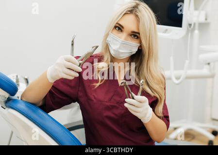 A dentist holds surgical instruments in his hands to remove a decaying tooth in the clinic Stock Photo