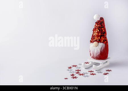 Doll Santa Claus on a sled with confetti on a white background place for text Stock Photo