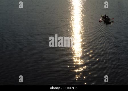 Kyiv, Ukraine, Two people kayaking on a calm river at golden hour, with the sunlight reflecting and sparkling across the water’s surface. Stock Photo