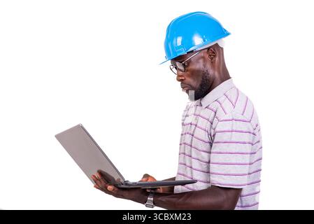 young man engineer wearing blue safety helmet and working with laptop. Stock Photo