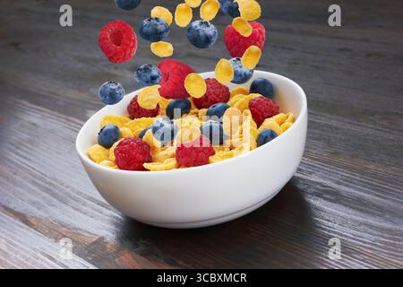 Falling fresh berries in corn flakes, on wooden background Stock Photo