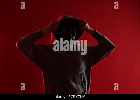Anonymity. Woman wearing mask on red background Stock Photo
