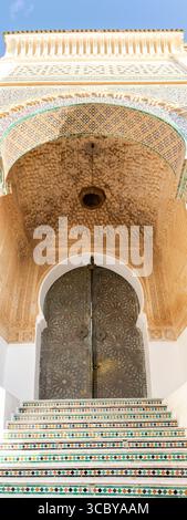 Sidi Boumediene mosque entrance door in Tlemcen, Algeria. Ornate Moroccan-style doorway with intricate geometric carvings, and mosaic tiled steps. Stock Photo