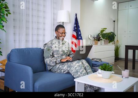 Smiling African American Female Soldier Using Laptop at Home Stock Photo