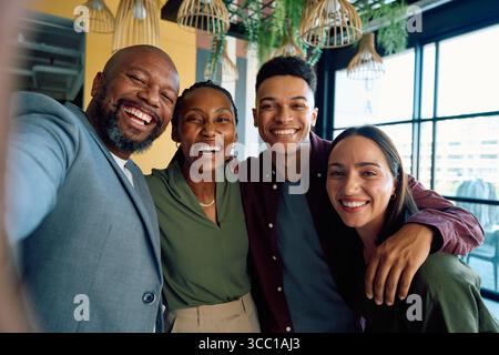 Portrait of cheerful diverse colleagues taking selfie together in office during daytime Stock Photo