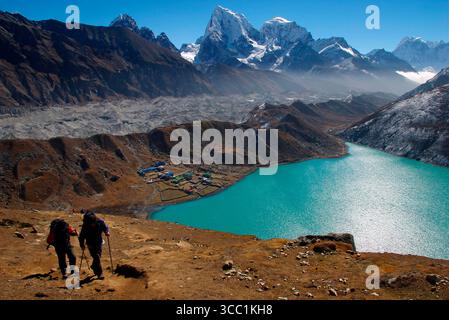 Trekkers climb Gokyo Ri ( Gokyo Peak ) in Nepal - with a backdrop of the third lake of the spectacular Gokyo valley. This valley is increasingly an in Stock Photo