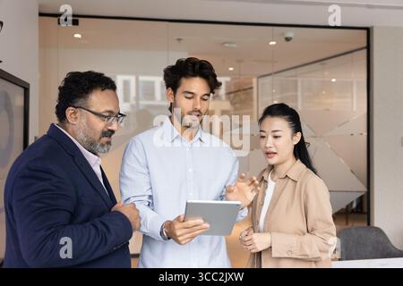 Diverse multiracial businesspeople group standing in office using tablet pc Stock Photo
