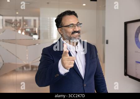 Smiling mature businessman looking at camera pointing finger at you Stock Photo