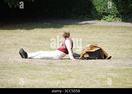 Man Relaxing Outdoors on Grass With Jacket and Bag. Salisbury, England Stock Photo