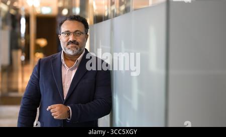 Friendly mature Indian businessman standing in office hall Stock Photo