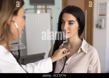 Positive beautiful young woman visiting cardiologist doctor for examination Stock Photo