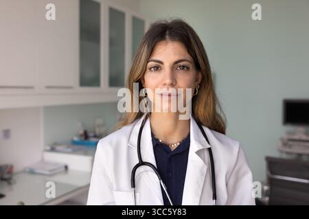 Serious friendly beautiful Hispanic female doctor wearing lab coat Stock Photo