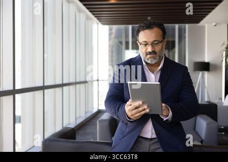 Senior Indian businessman using financial professional application on tablet Stock Photo