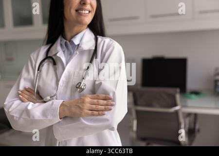 Confident successful happy young female doctor standing in clinic office Stock Photo