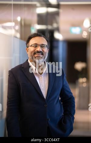 Positive older Indian company boss man standing in office hall Stock Photo
