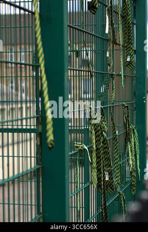 School ties hang from a metal fence, symbolising the end of the school year Stock Photo