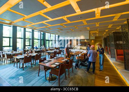 A spacious, modern restaurant in Four Seasons Hotel Kyoto. Natural light illuminates the open space, featuring neatly arranged tables and chairs. Idea Stock Photo