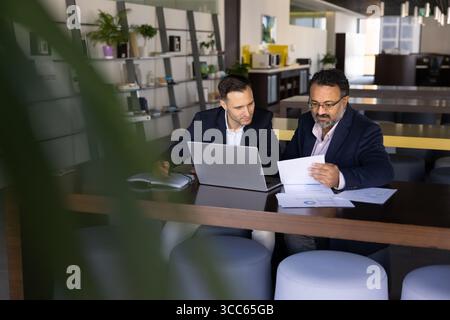 Busy younger and elder multiethnic business coworkers working at laptop Stock Photo