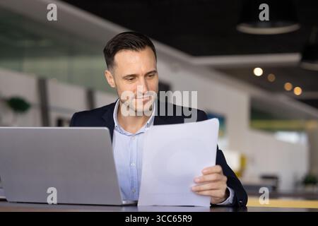 Positive Hispanic financial business professional man analyzing document Stock Photo