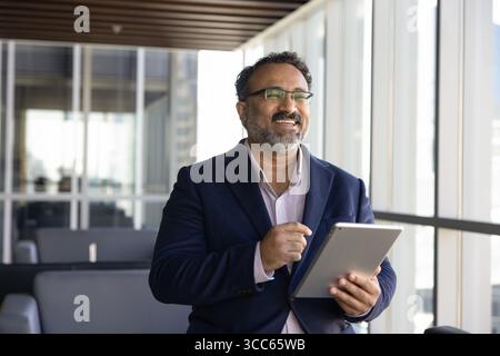 Cheerful happy older Indian business leader man using tablet Stock Photo