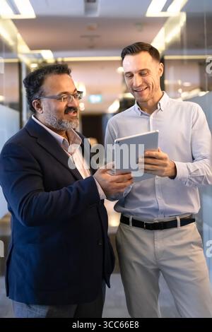 Senior Indian business leader asking younger colleague for technical support Stock Photo