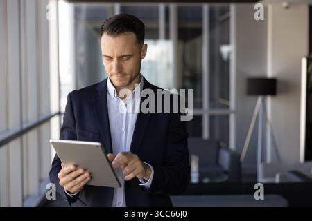 Focused busy Latin executive man using finance management application Stock Photo