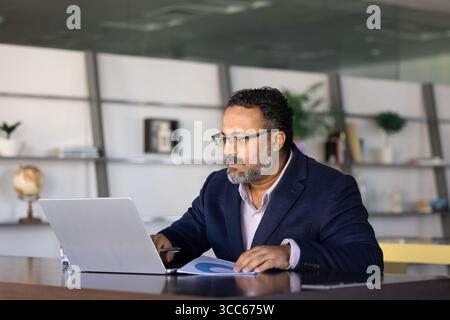 Serious busy elder Indian executive using online business application Stock Photo