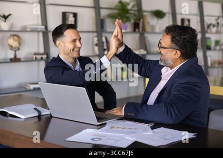 Two young and senior multiethnic businessmen making fist bump gesture Stock Photo